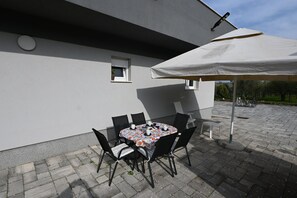An outdoor patio with a round table, chairs, and a large umbrella. - House Ivana (Pula)