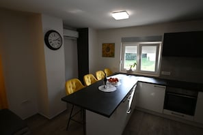 A kitchen with a dining table, chairs, a clock, and a window with blinds. - House Ivana (Pula)