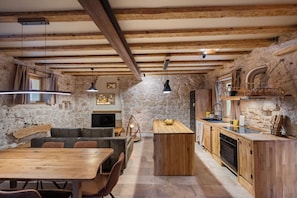 A rustic kitchen with stone walls, wooden beams, and a central island. - Apartment Heritage Stonehouse (Preko)