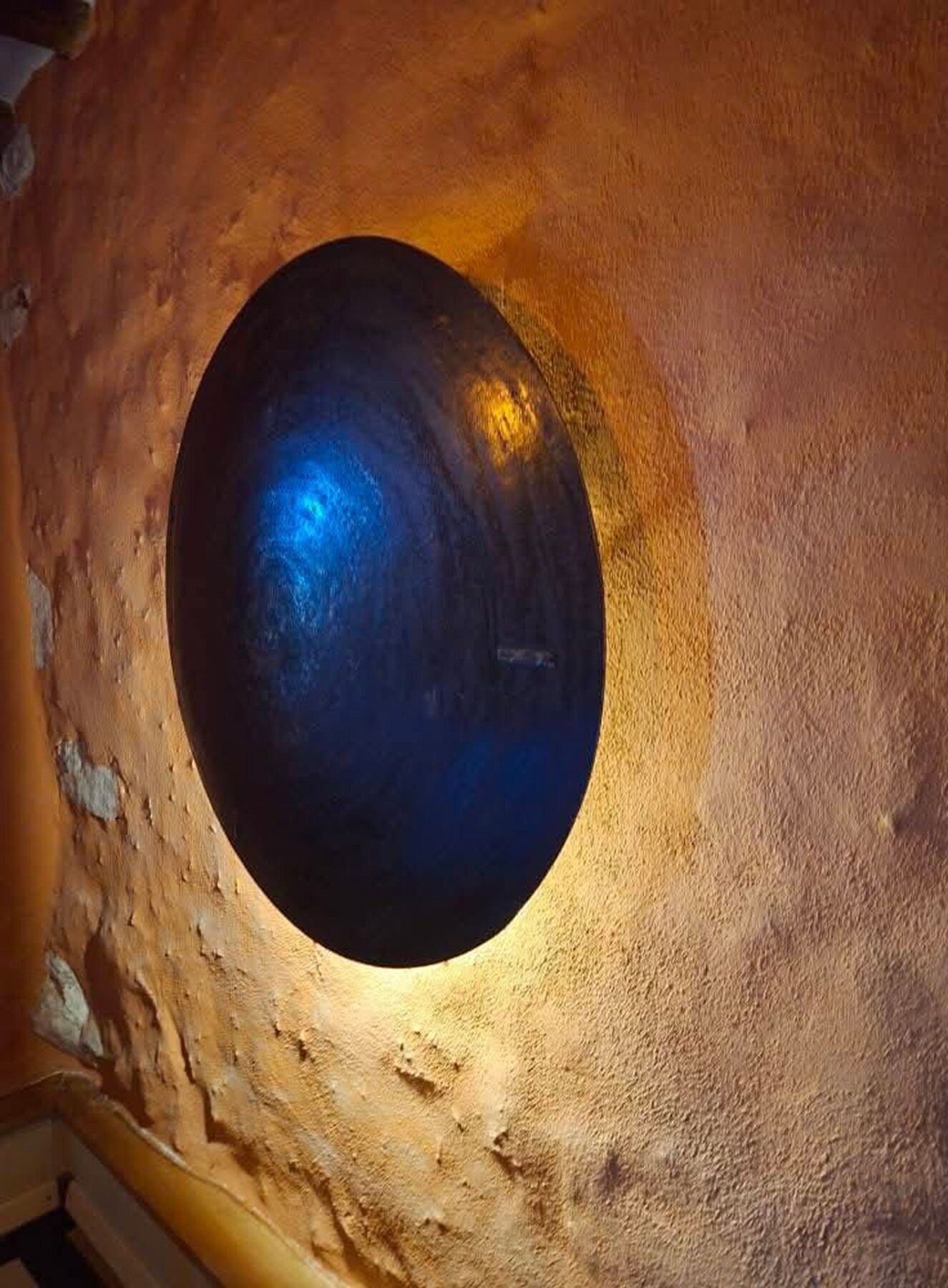 A circular skylight with a blue interior, surrounded by textured walls.