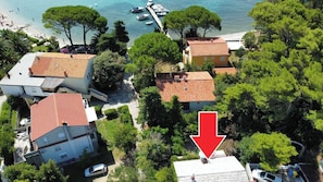An aerial view of a coastal residential area with houses, a dock, and boats. - Apartment Marina (Rab)