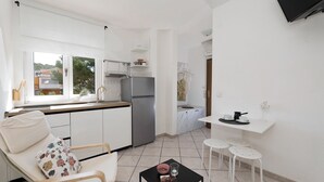 Eine kompakte Küche mit Kühlschrank, eine Essecke mit Stuhl und Tisch sowie eine kleine Kücheninsel mit Spüle.