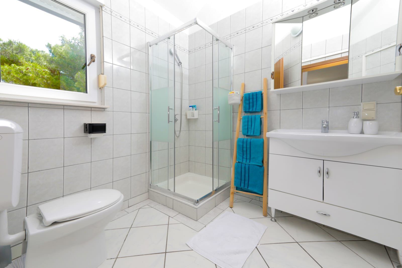 Une salle de bain moderne avec une douche à parois de verre, des toilettes, un lavabo avec un meuble-vasque et une fenêtre.