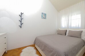 Ein Schlafzimmer mit einem Bett, einem Schminktisch, einem Wandhaken für Kleidung und einem Gemälde.