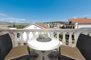 Ein Balkon mit Tisch und Stühlen, mit Blick auf eine Wohngegend mit Häusern und Hügeln.