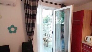 A dining area with a table, chairs, and a potted plant. There is a sliding glass door leading to an outdoor area with a table and chairs. - Apartments Andreja (Crikvenica)