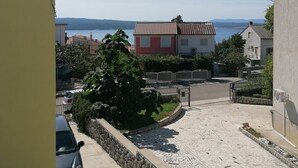 A residential area with a paved driveway, a parked car, and a building with a red and white facade. - Apartments Andreja (Crikvenica)