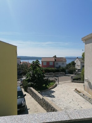 A residential area with a paved driveway, a parked car, and a building with a red and white facade. - Apartments Andreja (Crikvenica)