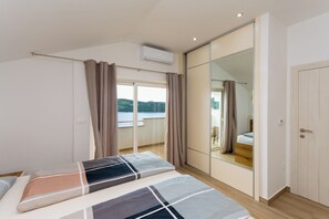 A bedroom with a bed, curtains, a sliding door, and a view of a balcony.