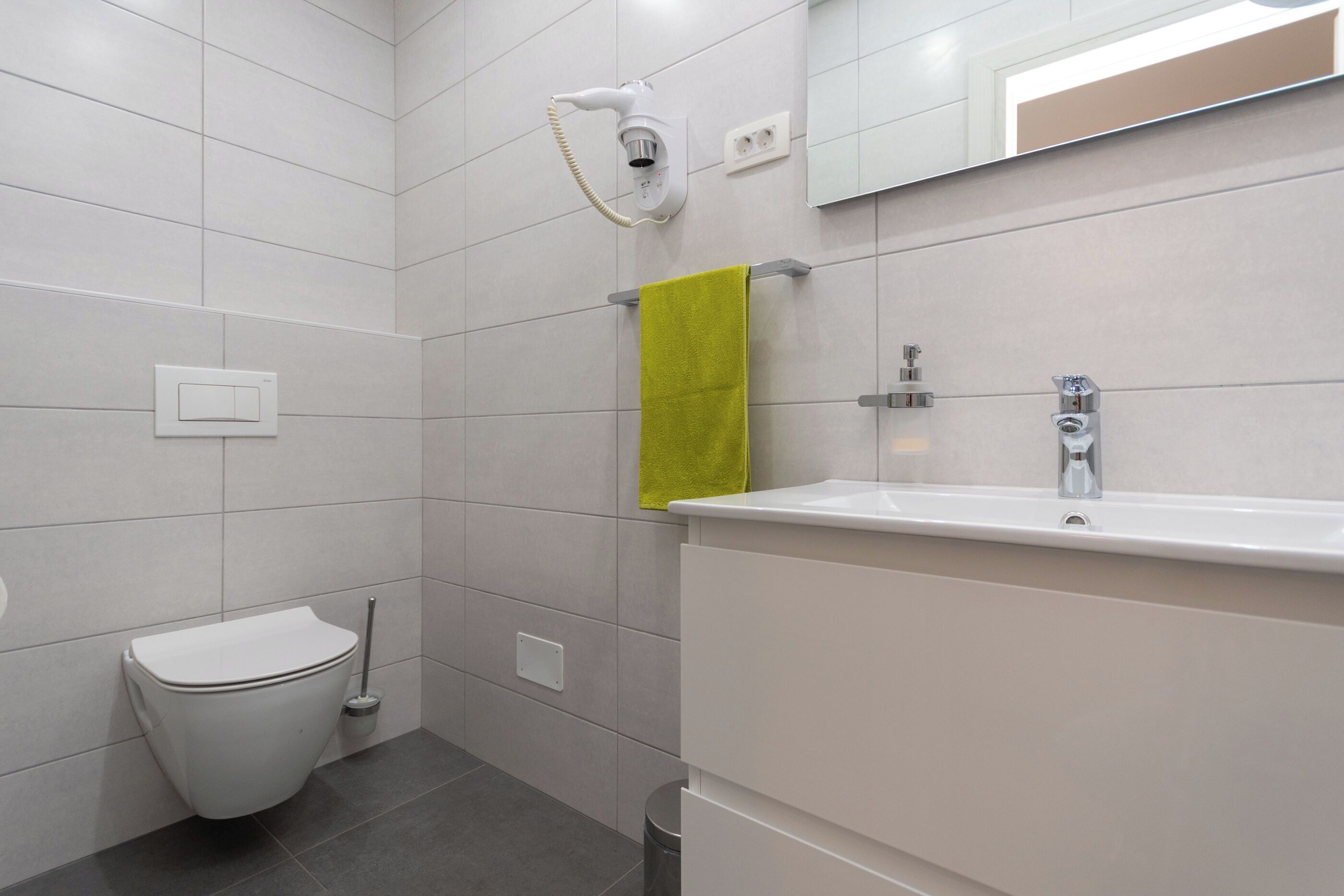 A bathroom with a toilet, a sink, a mirror, and a towel rack.