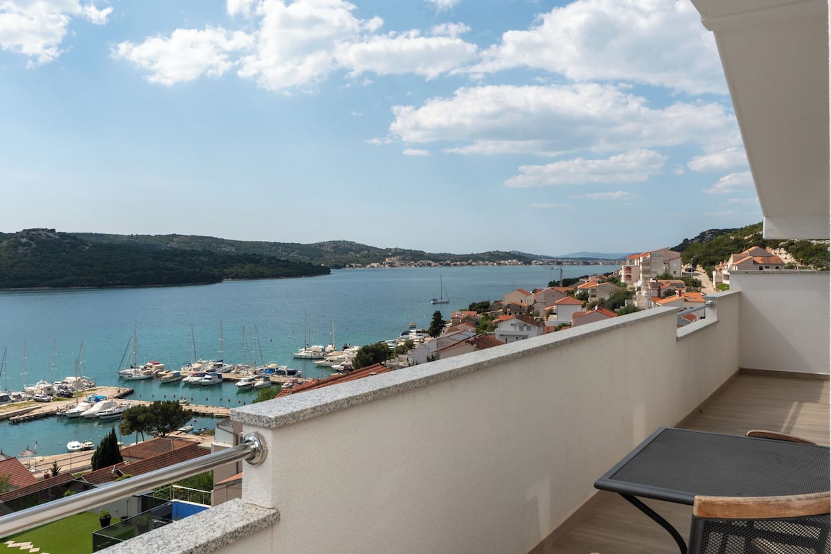 Ein Balkon mit Blick auf einen Hafen und sanfte Hügel in der Ferne.