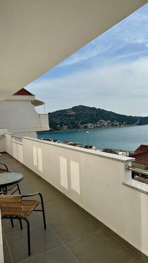 Ein Balkon mit Blick auf ein Gewässer und eine Hügelkette.