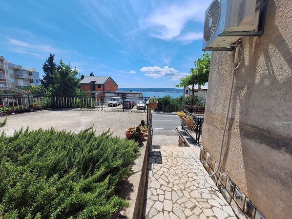 A paved courtyard with potted plants, a stone pathway, and a view of the sea. - Apartments Yasmin i Marina (Crikvenica)