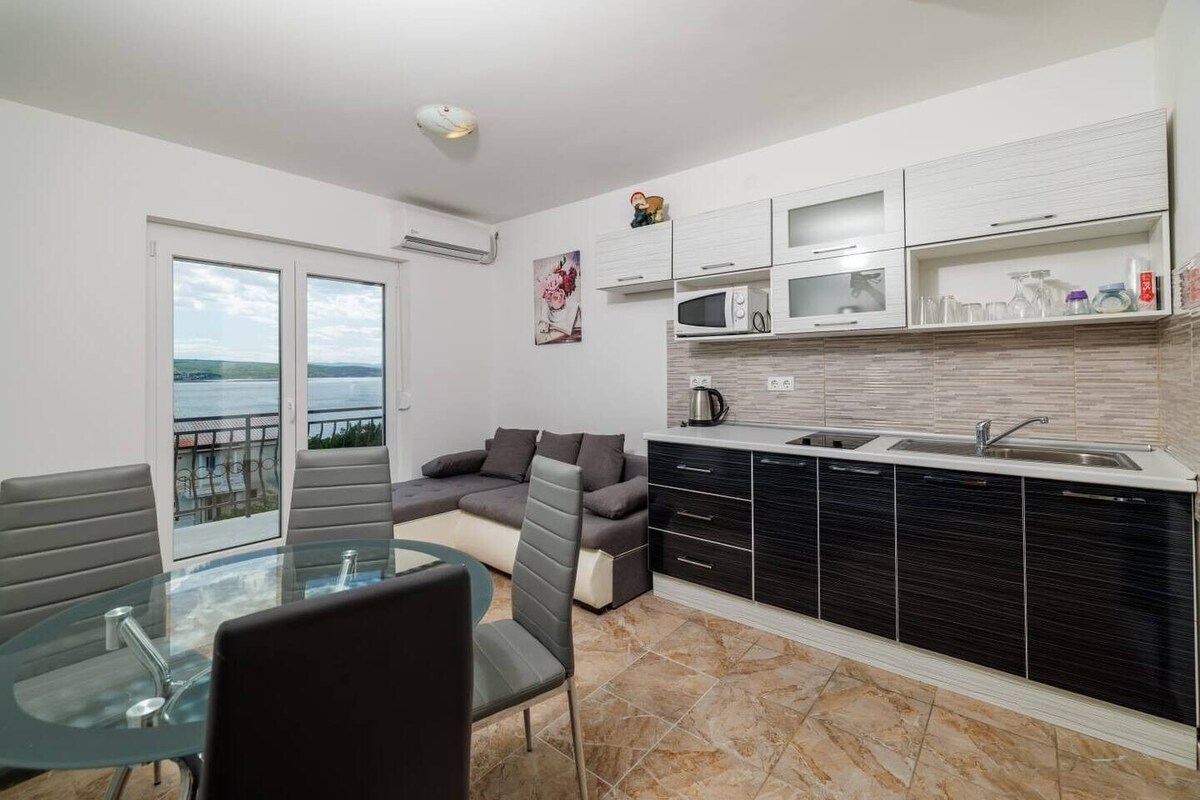 Una cocina moderna con comedor, sofá y vista al mar.