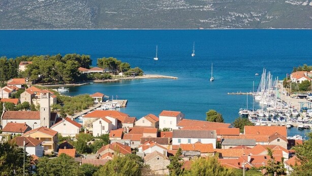 Un pueblo costero con edificios, un puerto deportivo y barcos.