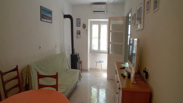 A living room with a sofa, a dining table, chairs, a TV, and a fireplace. - House Veli Iz Oldtown (Zadar)