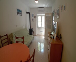 Una sala de estar con sofá, mesa de comedor, sillas, televisor y chimenea.