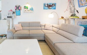 A modern living room with a sectional sofa, a white coffee table, and various wall art including a bird painting and a welcome sign. - House Pineta Art Home (Medulin)