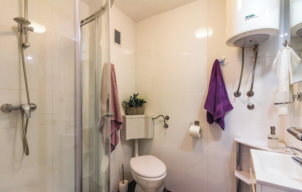A bathroom with a glass-enclosed shower, a toilet, and a sink.