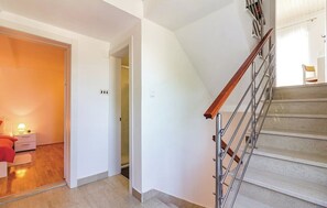 A staircase with a wooden handrail and metal balusters, leading to a room with a bed and a nightstand. - House Pineta Art Home (Medulin)