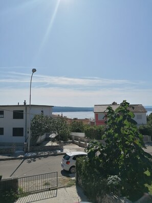 A residential area with a white building, a red building, and a parked car. - Rooms Andreja (Crikvenica)