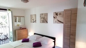 Ein Schlafzimmer mit Bett, Kleiderschrank, Schreibtisch und Fenster.