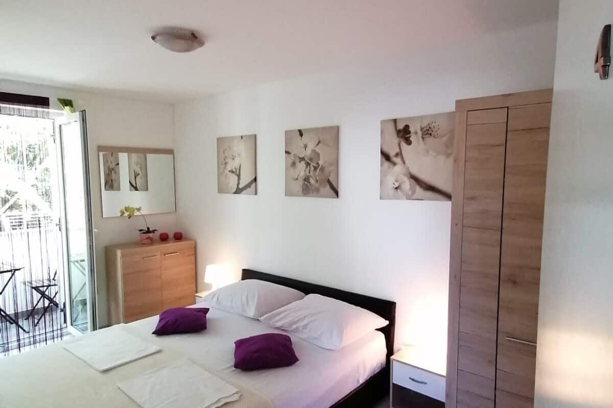 Un dormitorio con cama, armario, escritorio y ventana.
