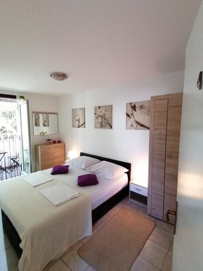 Ein Schlafzimmer mit Bett, Kleiderschrank, Schreibtisch und Fenster.
