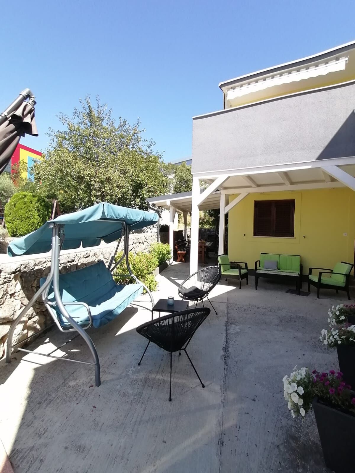 An outdoor patio with a covered seating area, a table, and a chair.