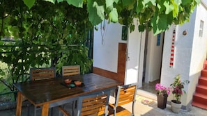 Ein Essbereich im Freien mit Tisch und Stühlen, einem Blumentopf und einer Tür mit einem roten Notausgangsschild.