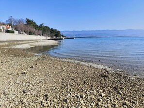 A pebbled beach with a clear view of the water and distant mountains. - Apartment By the sea (Dobrinj)