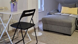 Quarto com mesa de jantar, cadeira, sofá, abajur e janela.