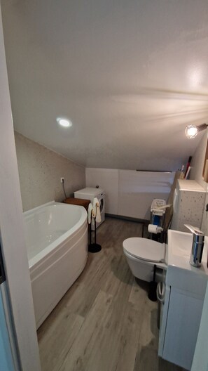 A compact bathroom with a bathtub, toilet, and a small sink area. - Apartment By the sea (Dobrinj)