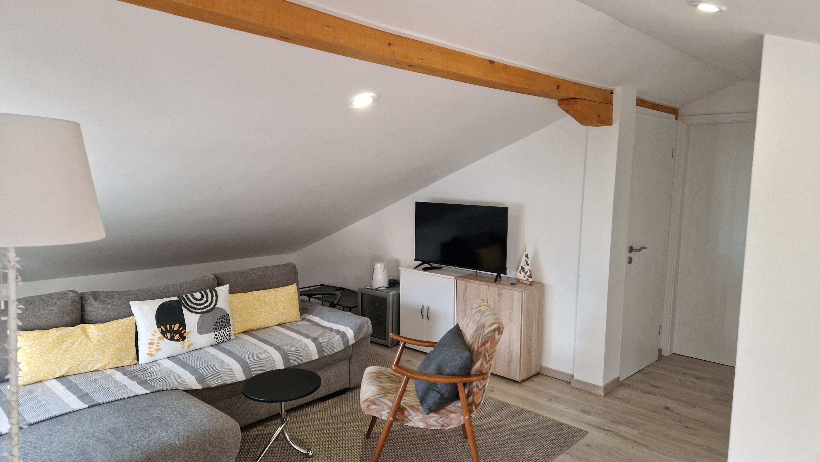 Uma sala de estar moderna com um sofá, uma televisão e um armário de madeira.