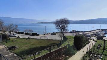 A coastal view with a parking area, a grassy field, and a body of water.
