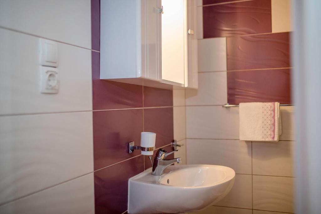 Une salle de bain avec un lavabo blanc, un porte-gobelet et un porte-serviettes.