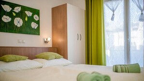 Ein Hotelzimmer mit Bett, einem Gemälde, einem Schrank und einem Fenster mit Vorhängen.