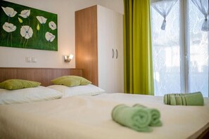 Ein Hotelzimmer mit Bett, einem Gemälde, einem Schrank und einem Fenster mit Vorhängen.