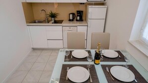 Ein Esstisch für vier Personen, gedeckt mit Champagner, zwei Weingläsern und Besteck.