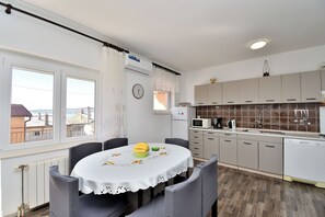 Eine Küche mit Esstisch, Stühlen, Schränken, einer Mikrowelle und einer Uhr an der Wand.