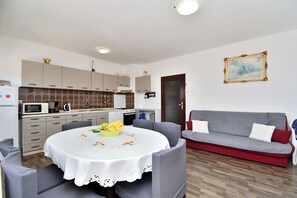 Eine moderne Küche mit Essbereich, einem grauen Sofa und einem Gemälde an der Wand.