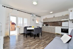 Eine moderne Küche mit Essbereich, einer Couch und Blick ins Freie.