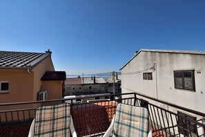 Ein Balkon mit zwei Stühlen, einem Ziegeldach und Blick auf angrenzende Gebäude.
