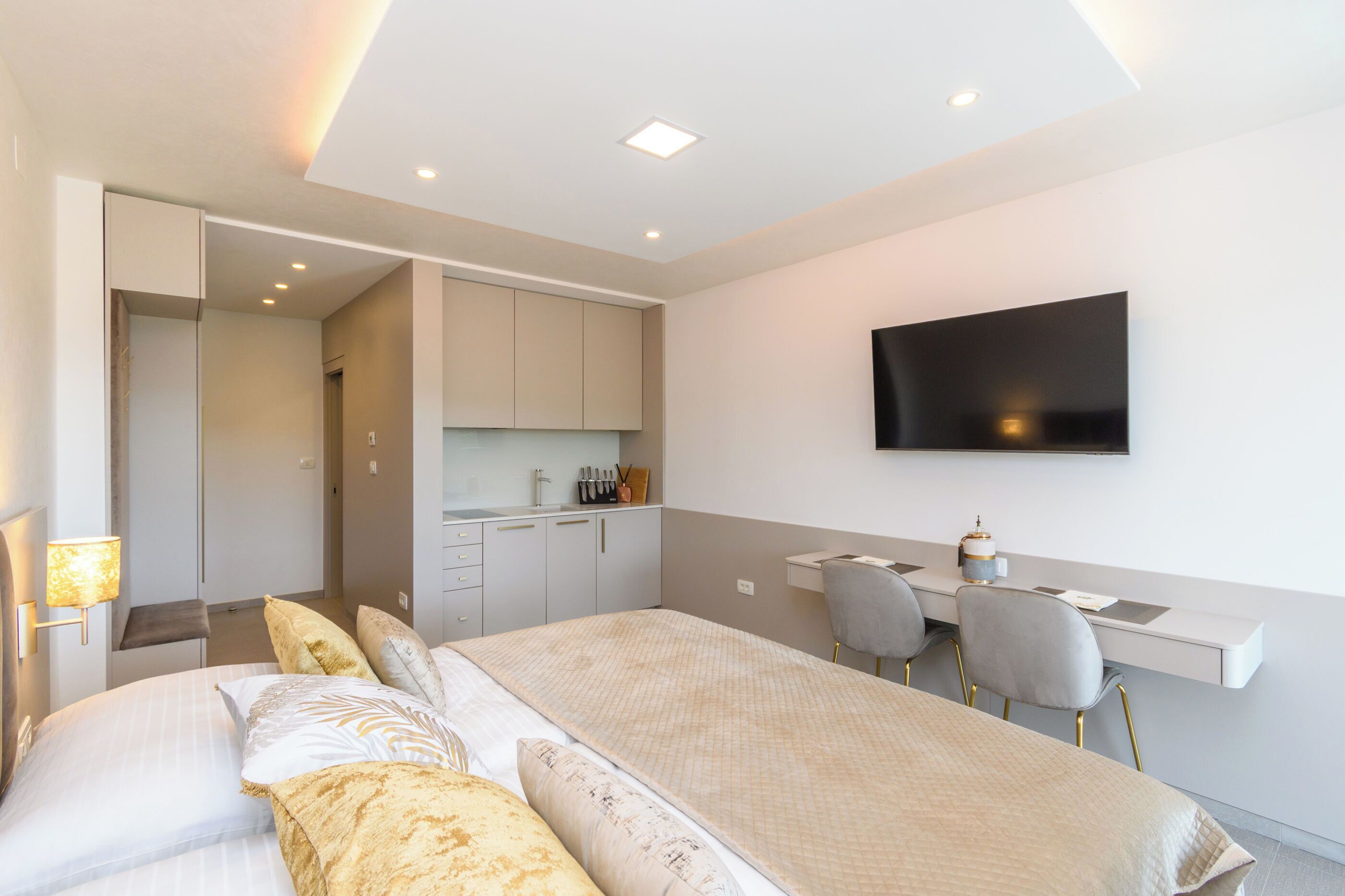 A modern hotel room with a large bed, a desk, and a TV.