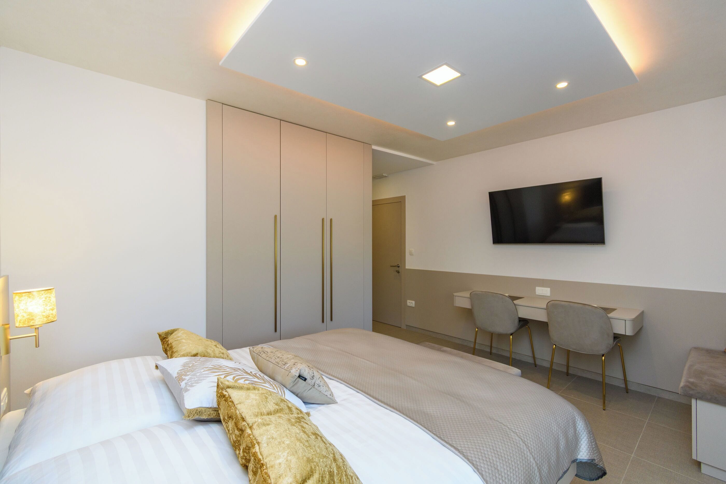 Una habitación de hotel moderna con una cama grande, un escritorio y un televisor montado en la pared.