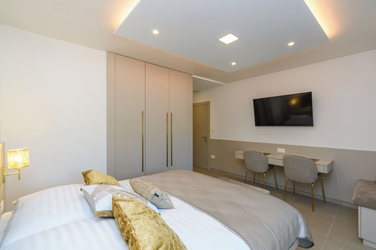 A modern hotel room with a large bed, a desk, and a TV mounted on the wall.
