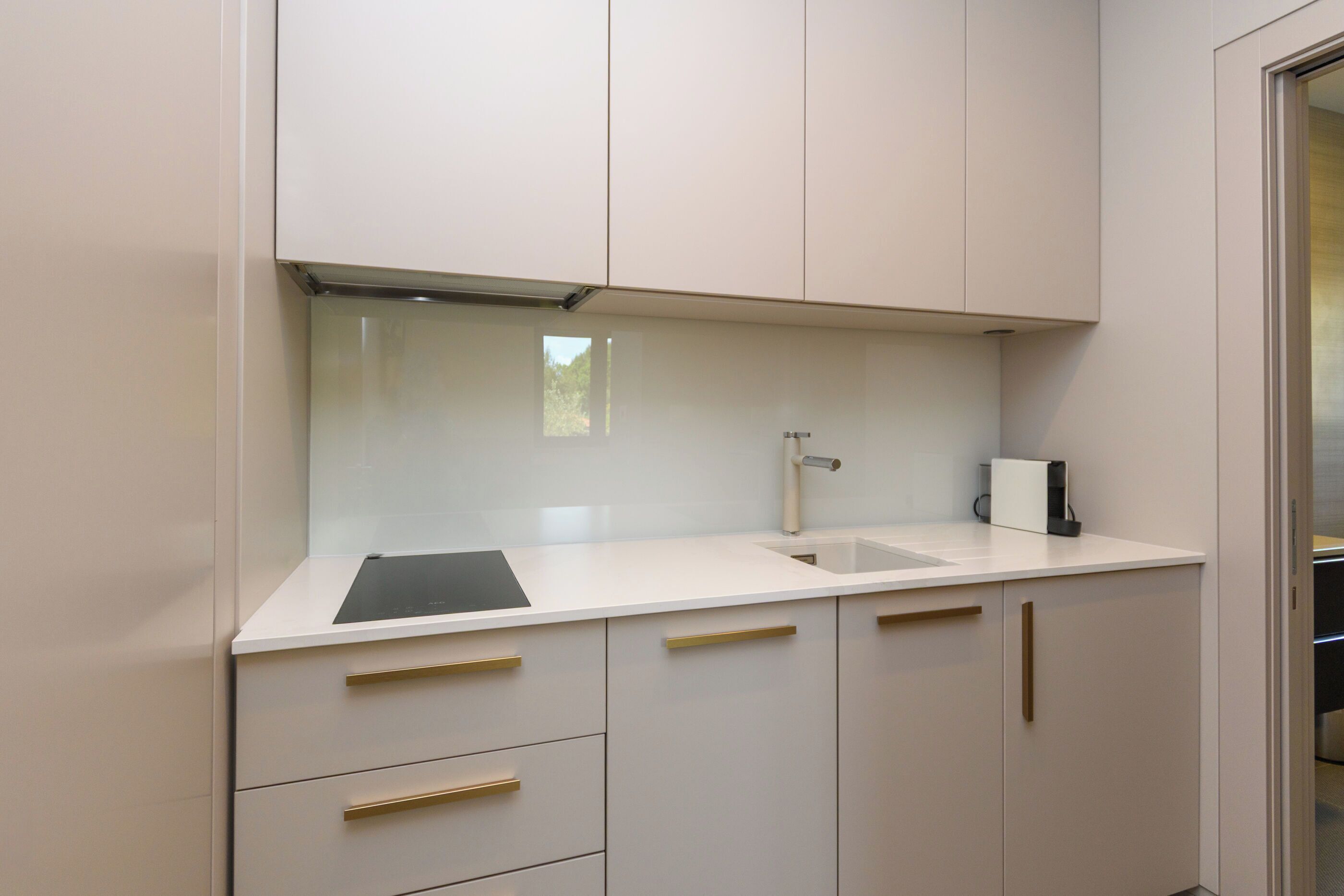A modern kitchen with white cabinets, a black countertop, and a stainless steel sink.
