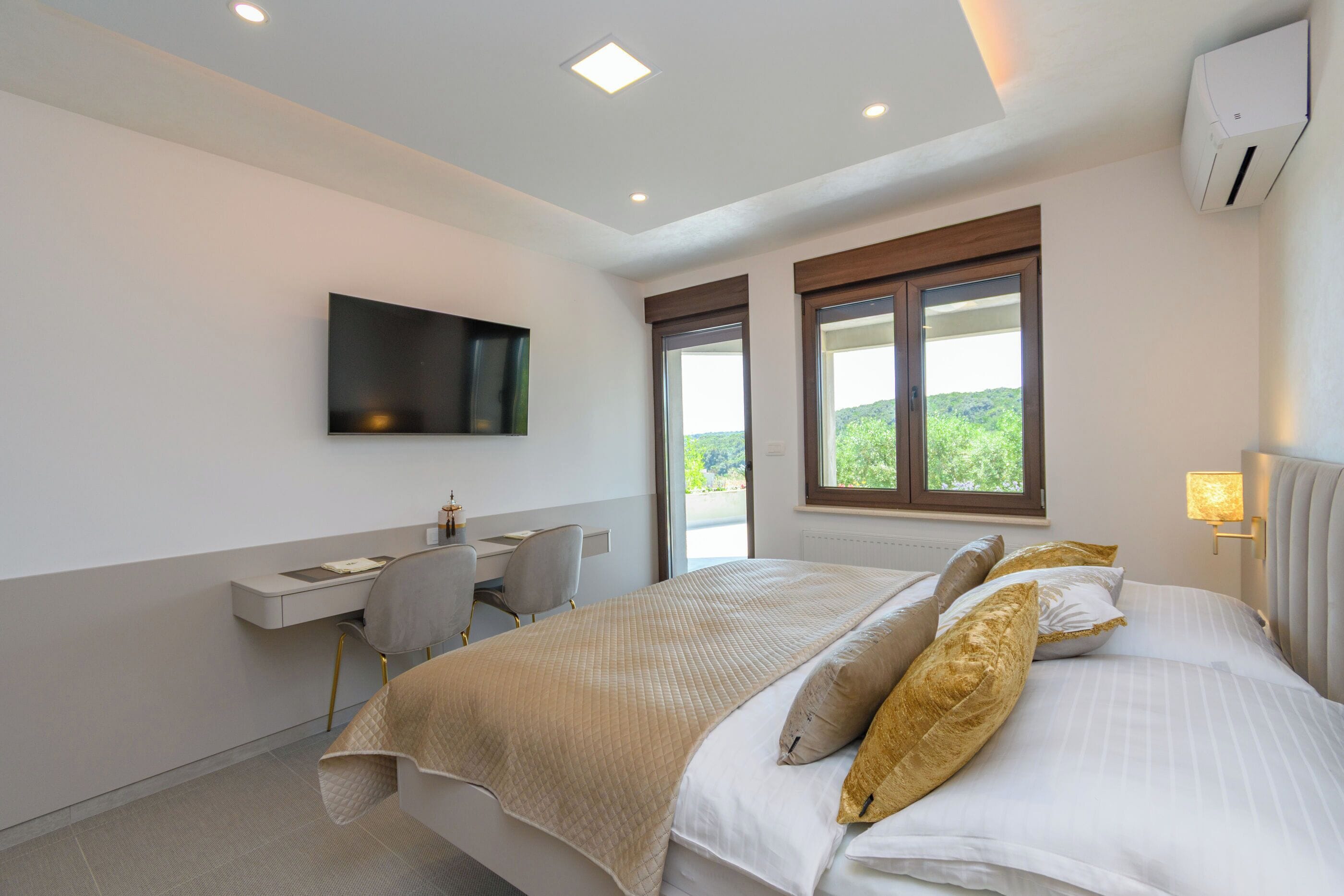 Un dormitorio con cama, escritorio, silla, televisor y ventana con vistas.