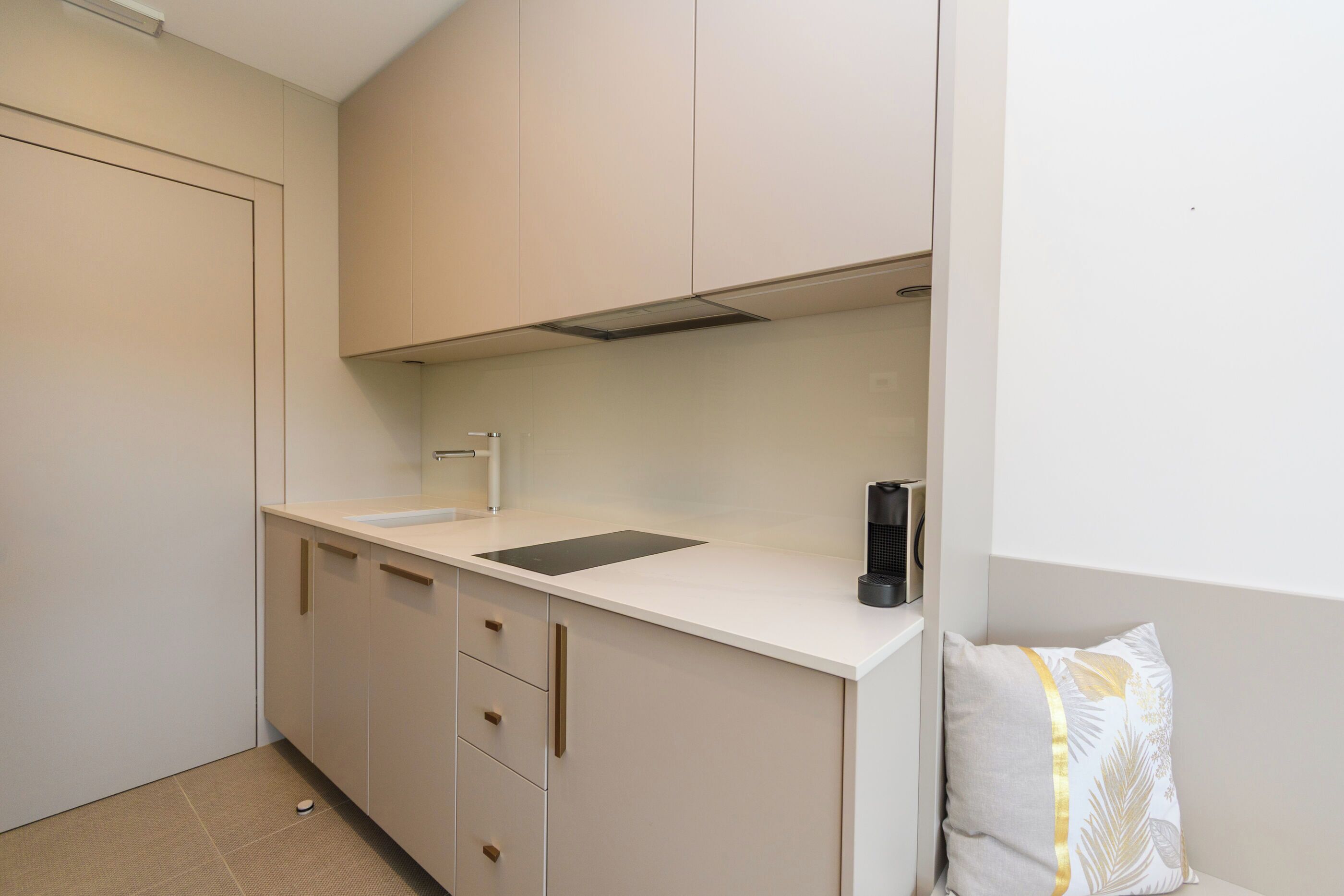 A compact kitchen with a sink, cabinets, and a modern stove.
