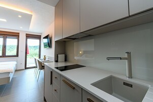 Una cocina moderna con un lavamanos grande, un televisor de pantalla plana sobre la encimera y un comedor con una silla y una mesa.